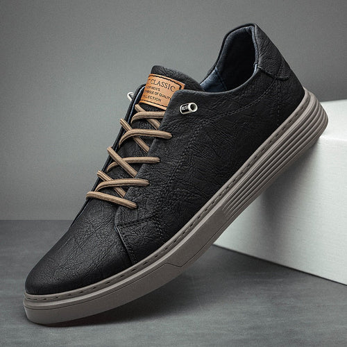 Black leather oxford sneaker with beige laces and gray sole on a gray background